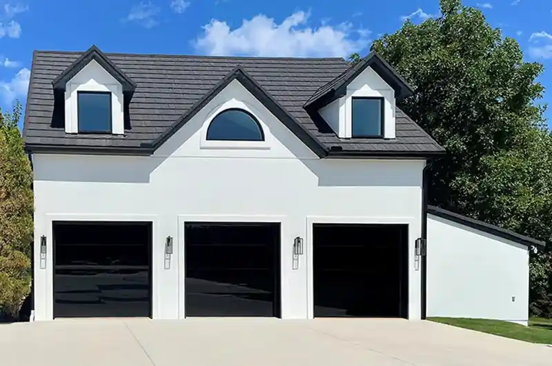 Triple opaque black glass frameless garage doors on white home